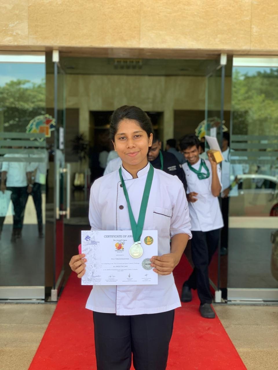 Thilini in chef uniform with culinary awards